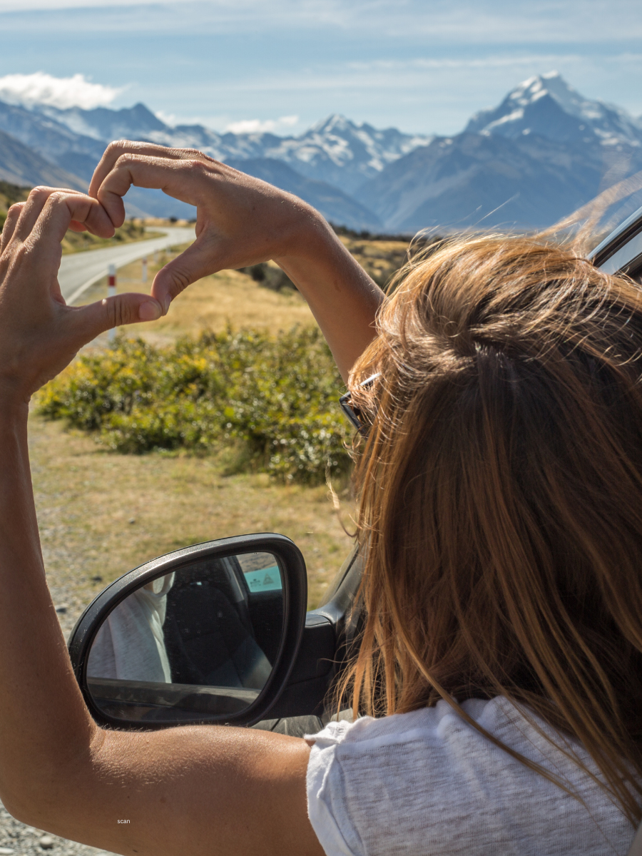 A person enjoying a road trip with their arm out the car window.