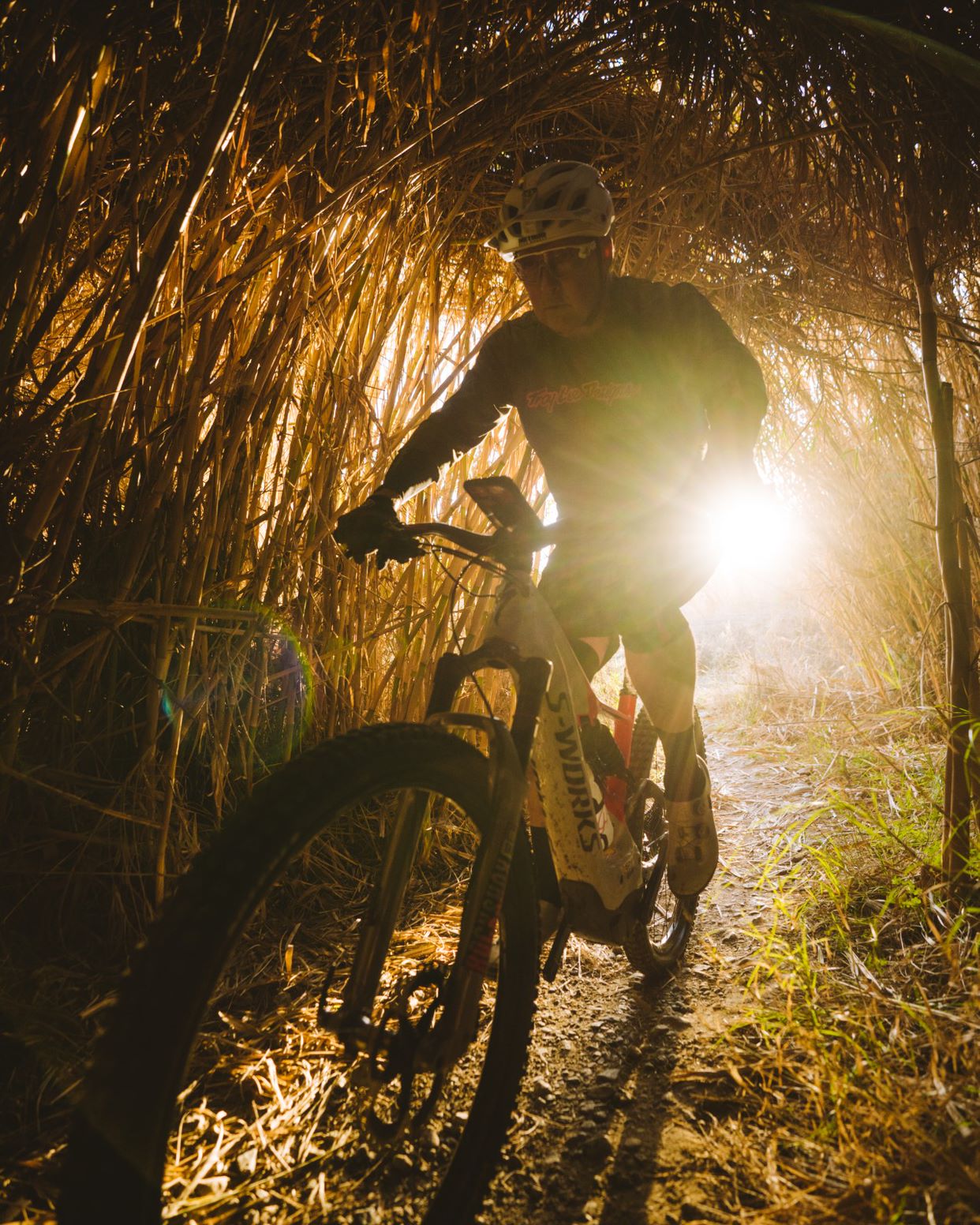 A mountain biker rides through a dark tunnel while looking at his phone, mounted on a ROKFORM Phone Mount. The Text reads “Mountain Bike Maintenance for Beginners”